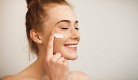 Woman applying cream to cheek